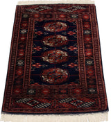 Vintage Bokhara rug from an angle, showing the lustrous pile and repeating gul medallions.