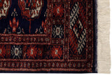 Fine guls and intact navy selvage on a vintage Bokhara rug corner with clean ivory fringe.