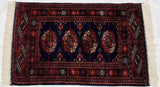 Repeating rust and ivory gul medallions on the lustrous indigo blue field of a vintage Bokhara rug.