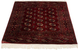 Plush wine red Bokhara rug pile, showcasing repeating navy and rust gul medallions.