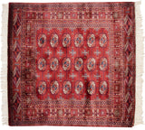 Vintage Bokhara rug corner with wine red field, intricate geometric border, and side selvage.