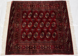 Intricate geometric borders and wine red gul medallions at the fringed Bokhara rug corner.
