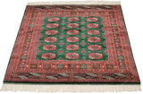 Lustrous mallard green pile of a vintage Bokhara rug with repeating rust-colored gul medallions.