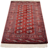 Angled view of a vintage Bokhara rug highlighting the luster of its dense wine-red and navy pile.