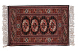 Vintage fine Bokhara rug with repeating elephant's footprint guls in rust, black, and ivory.