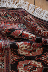 Folded vintage Bokhara rug highlighting the plush, silk-like texture and detailed weave of its wool pile.