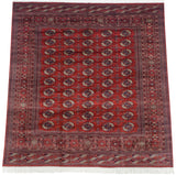 Angled perspective of a fine Bokhara carpet with navy and ivory gul medallions on a cherry red field.
