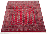 Angled view of a vintage Bokhara carpet highlighting the lustrous sheen on its red wool.