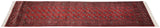 Angled perspective of a vintage Bokhara runner highlighting its lustrous pile and gul pattern.