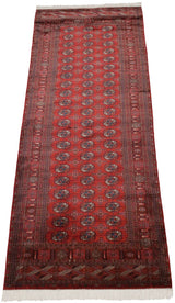 High-angle view of a vintage Bokhara runner with repeating gul medallions on a brick-red field.