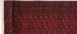 Partially rolled view of a fine Bokhara rug showing its detailed borders, gul medallions, and ivory fringe.