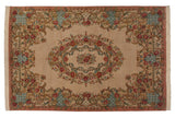 Corner of a vintage Bulgarian carpet showing Rococo floral vines in dusty rose and powder blue.