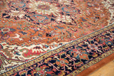Intricate navy border featuring colorful floral and geometric patterns on the rust Heriz rug.