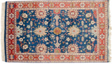 A geometric terracotta border frames the sapphire blue field with sprawling floral palmettes.