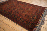 The lustrous wool pile and intricate charcoal and rust gul pattern of a Bokhara rug.