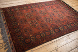 Lustrous wool pile of a vintage Bokhara rug with repeating geometric gul medallions in rust and charcoal.