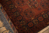 Intact charcoal fringe and side cord selvage on a vintage Bokhara rug with rust and saffron geometric motifs.