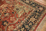 Elaborate vinery, floral blossoms, and tendrils in copper, navy, and beige on a vintage Serapi carpet.
