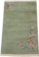 Lower right corner of Japanese Art Deco rug, sprawling floral vines in blush, blue, fringe.