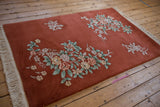 Art Deco rug floral bouquet in celadon, ivory, dusty rose, and mauve on copper field.