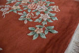 Art Deco rug detail: Copper field, green leaves, mauve floral sprays, and fringe.