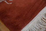 Close-up of the vintage Art Deco rug's copper pile and braided ivory fringe.