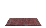 Angled view of a vintage Mahal carpet showing its full pile and gem-like colors in a floral lattice pattern.