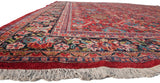 Angled view of a vintage Mahal carpet's lush pile, showcasing the gem-toned floral border and fringe.