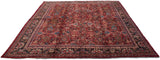 High-angle view of a vintage Mahal carpet showing its ruby red floral field and charcoal navy border.