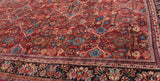 Angled detail of a vintage Mahal carpet's ruby field and intricate floral navy border.