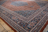 Detailed corner of the vintage Indian Bijar carpet, featuring its denim blue border and Herati motif.