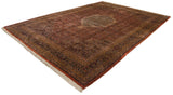 Detailed corner of vintage Indian Bijar carpet: copper, navy, gold Herati pattern, plush pile, white fringe.