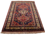 The full length of a vintage Indian Shiraz rug with geometric medallions and intricate borders viewed from an angle.