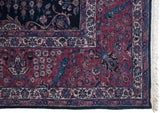 Corner detail of a fine Sarouk's aubergine floral border, indigo field, and original selvage.