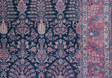 A fine Sarouk carpet's indigo field with flowering vases contrasts with its intricate cochineal red border.