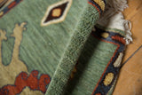 Full celadon green pile, variegated terracotta and navy border of this Armenian pictorial rug.