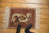 Sprawling ivory dragon with blossoms on an abrashed aubergine Armenian pictorial rug.
