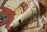 Thick ivory pile, madder red figural detail, and creamy fringe on the rolled Armenian rug.