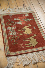 An angled view of the vintage pictorial Armenian rug showing its full pile texture and herdsman design.