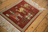 An angled view of the pictorial Armenian rug showing the herdsman, camels, and chevron border.