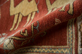 Close view of the plush, rust-red pile and hand-knotted camel design on a vintage rug.