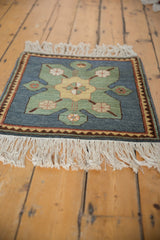 Angled view of a vintage Yerevan square rug highlighting its starburst design and thick fringe.
