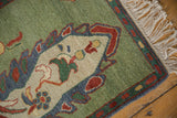 Armenian Peacock rug corner: emerald green field, denim blue border, ivory plant motif, and fringe.