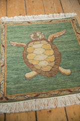 Close-up of pictorial turtle's shell on pale emerald green field with meandering vine border.