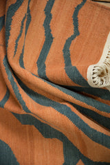 Hand woven kilim texture, pale rust and dusty charcoal tiger stripes, and ivory fringe.