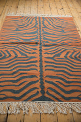 Hand woven tiger kilim showing pale rust, charcoal stripes, and white fringe.