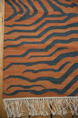 Hand-woven kilim fringe and pale rust, charcoal tiger stripe pattern.