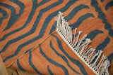 Hand-woven Tiger Kilim rug detail: pale rust, charcoal stripes, subtle abrashes, and white fringe.