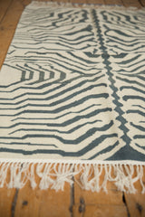 White fringe and hand-woven ivory, charcoal pattern on vintage zebra kilim rug.