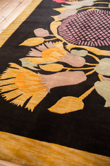 Plush black pile of an Art Deco rug with oversized gold, mauve, and soft green floral designs.